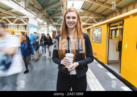 Porträt der rothaarige junge Frau mit Kaffee auf Plattform, Berlin, Deutschland Stockfoto