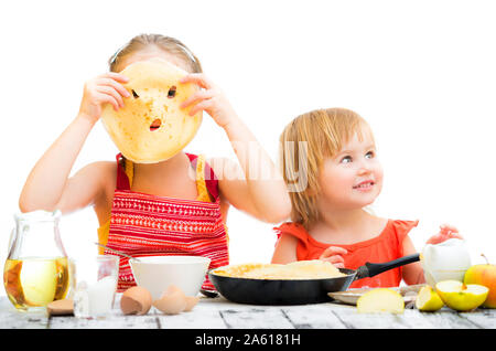 Lustige Schwestern kochen Pfannkuchen am Küche auf einem weissem Hintergrund Stockfoto