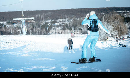 Mädchen auf Snowboard auf snowhill Ansicht von hinten Stockfoto