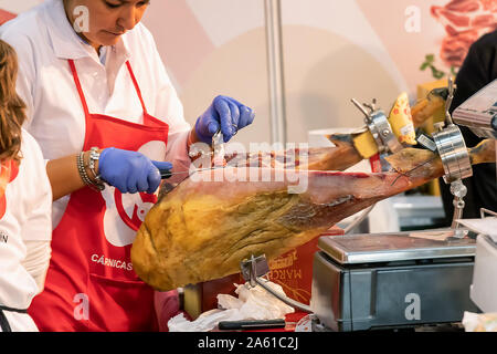 Aracena, Huelva, Spanien - Oktober 20, 2019: Frau Metzger schneiden Scheiben eines spanischen Iberian Serrano Schinken in 2019 Iberico Schinken Messe von Aracena Stockfoto