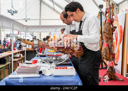 Aracena, Huelva, Spanien - Oktober 20, 2019: Metzger schneiden Scheiben eines spanischen Iberian Serrano Schinken Stockfoto