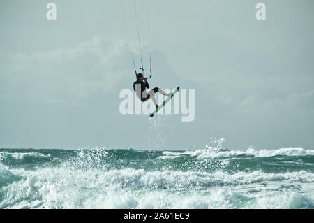 Kite Surfer Springen eine brechende Welle und fliegen durch die Luft, durch die Drachen aufgehoben, Atlantikküste, Lacanau-Océan, Frankreich. Stockfoto