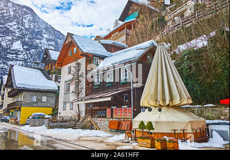 HALLSTATT, Österreich - 21. Februar 2019: Der Winter Stadtbild mit verschneiten Häuser, geschlossene Cafés im Freien und felsigen Bergen im Hintergrund, im Februar Stockfoto