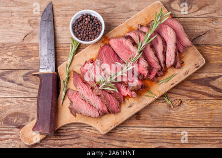 In Scheiben geschnitten Medium gebratenes Rindfleisch auf Holz Schneidebrett, Jäger Messer Stockfoto