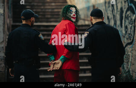 Dnipro, Ukraine - Oktober 22, 2019: Zwei Polizisten schildert Verhaftung von cosplayer in das Bild eines Verrückten clown Arthur Fleck aus der psychologischen thril Stockfoto