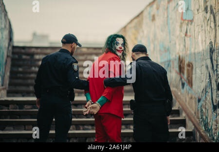 Dnipro, Ukraine - Oktober 22, 2019: Zwei Polizisten schildert Verhaftung von cosplayer in das Bild eines Verrückten clown Arthur Fleck aus der psychologischen thril Stockfoto