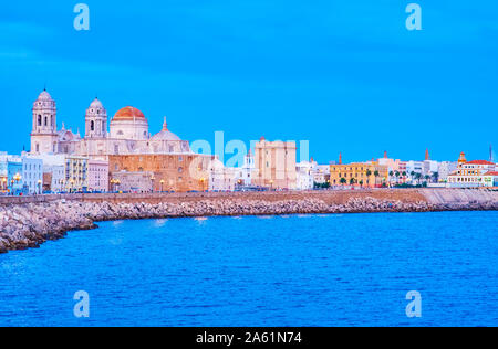 Die Kurven Küste der Altstadt von Cadiz mit erstaunlichen Abend Beleuchtung von mittelalterlichen Dom und kleine Häuser am Ufer, Spanien Stockfoto