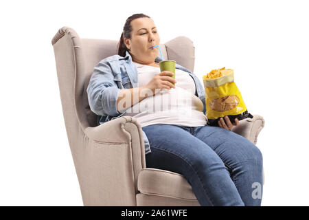 Übergewichtige Frau in einen Sessel Essen der Trödelnahrung auf weißem Hintergrund sitzen Stockfoto