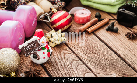 Bewegung, Fitness und Arbeiten auf Weihnachten und ein glückliches neues Jahr Konzept, Kurzhanteln, Springseil und Weihnachten Ornamente mit Schneemann und Merr Stockfoto