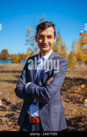 Männliche Herbst Mode. Stattlicher Mann mit grauen Anzug und Zubehör im Freien. Porträt der jungen Kerl in stilvoller Kleidung Stockfoto