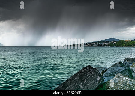 Ansicht der Stadt von Clarens am Ufer des Genfer Sees und dunklen regnerischen Wolken. Montreux, Schweiz. Stockfoto