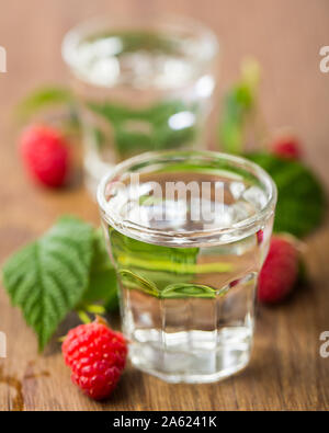 2 Gläser himbeere Schnaps mit Himbeeren auf Holzbrett Stockfoto