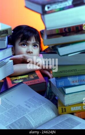 Ein sechs Jahre altes Mädchen starrte auf eine unglaublich große Auswahl an Lehrbüchern Stockfoto