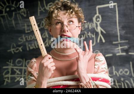 Humorvoll Foto einer Lehrerin vor ihrem Klassenzimmer Tafel gebunden Stockfoto