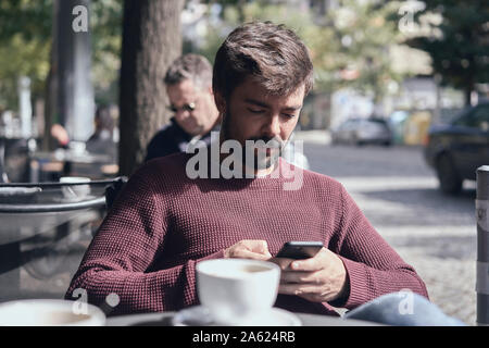 Attraktiven jungen bärtigen Mann mit seinem Smartphone im Cafe Stockfoto
