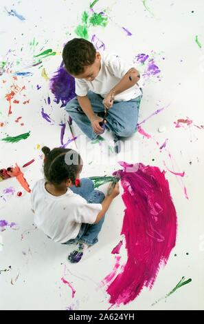 Ansicht von oben der afroamerikanischen Kinder malen auf eine große weiße Oberfläche mit Aquarellfarben Stockfoto