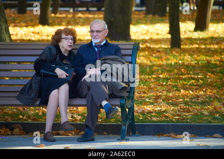Charkow, Ukraine - Oktober 14, 2019: Elegante ältere Paare sitzen auf einer Bank im Herbst Park Stockfoto