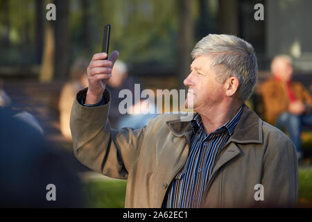 Charkow, Ukraine - Oktober 14, 2019: Männer auf der Straße fotografieren mit Handy, Hintergrund ist blured Stadt Stockfoto