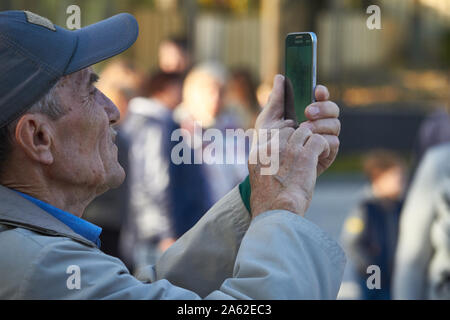 Charkow, Ukraine - Oktober 14, 2019: Männer auf der Straße fotografieren mit Handy, Hintergrund ist blured Stadt Stockfoto