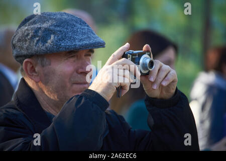 Charkow, Ukraine - Oktober 14, 2019: Männer auf der Straße fotografieren mit Handy, Hintergrund ist blured Stadt Stockfoto