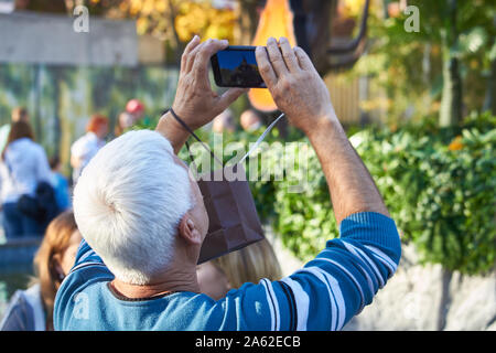 Charkow, Ukraine - Oktober 14, 2019: Männer auf der Straße fotografieren mit Handy, Hintergrund ist blured Stadt Stockfoto