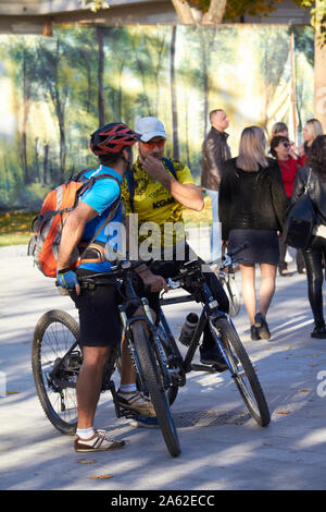 Charkow, Ukraine - Oktober 14, 2019: Zwei männliche Radfahrer sterben und Reden in einer Stadt park Stockfoto