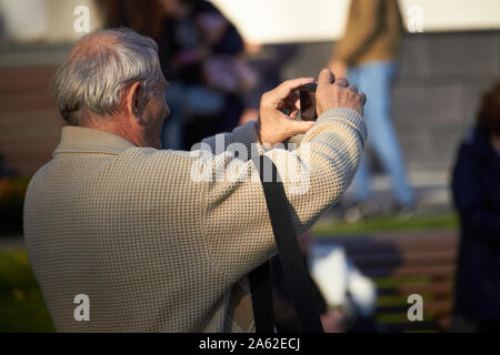 Charkow, Ukraine - Oktober 14, 2019: Männer auf der Straße fotografieren mit Handy, Hintergrund ist blured Stadt Stockfoto