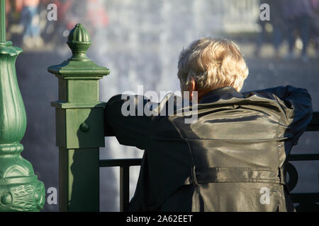 Charkow, Ukraine - Oktober 14, 2019: ältere Frau auf das Geländer der Brücke lehnte und sieht am Brunnen Stockfoto
