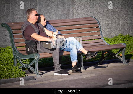Charkow, Ukraine - Oktober 14, 2019: Das mittlere Alter Paar mit einem kleinen Hund sitzen auf einer Bank im Herbst Park Stockfoto
