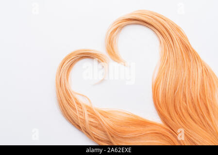 Honig blond in der Form des Herzens. Ein Beispiel für die Frisur. Menschliche, natürliche Honigfarbe blonde Haare auf weißem Hintergrund isoliert. Stockfoto