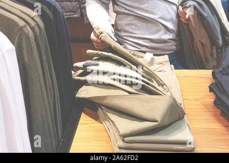 Auswahl und Kauf. Präsentation der Dinge im Store. Ein Mann beschließt, die Dinge in einen Men's speichern. Männer shopping Stockfoto