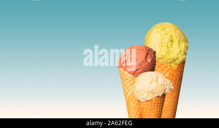 Kugeln Eis auf blauem Hintergrund. Süße Nachspeise in der Wafer Kegel. Natürliche Eis mit Schokolade, Pistazie und Vanille oder Cream Geschmack. Kostenloser co Stockfoto