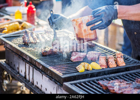 Gebratenes Fleisch am Grill zubereitet. Gegrilltes kebab Kochen auf Metall Spieß. BBQ frisches Fleisch Scheiben schneiden. Holzkohle Grill und Flammen, Street Food. Stockfoto