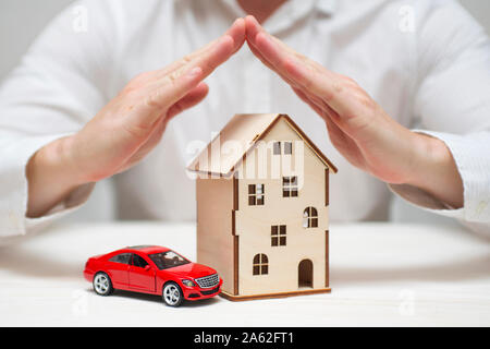 Versicherung Konzept der Auto Versicherung, Haus Versicherung auf den Schutz durch die Hände. Haus und Auto Versicherung Konzept. Stockfoto