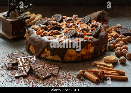 Jawor, Polen - Frühjahr 2018: Eine köstliche hausgemachte Cheesecake mit Schokoladenüberzug mit Muttern, Delikatessen, Cookies und Wafer eingerichtet. Stockfoto