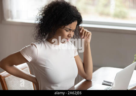 Ungesunde betonte junge schwarze Frau mit Muskeln Rückenschmerzen. Stockfoto