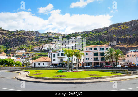 Ribeira Brava, Madeira, Portugal - Sep 9, 2019: Malerisches Dorf mit Palmen auf der Straße. Häuser auf dem Hügel im Hintergrund. Grüne Bäume und Bananen Plantage unter den Gebäuden. Stockfoto