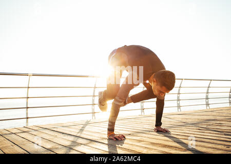 Junger Mann eine bakasana, Kran Pose während eines intensiven Yoga Praxis Stockfoto