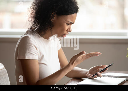 Wütend afrikanische amerikanische junge Frau durch defektes Gerät gereizt. Stockfoto