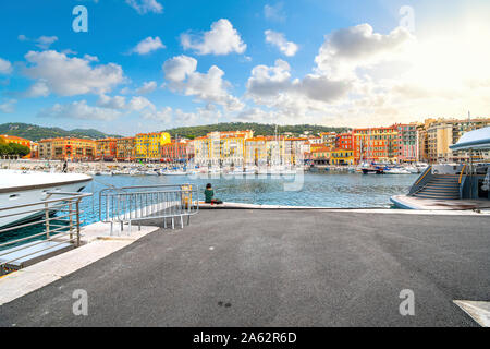 Eine Frau isst ihr Mittagessen allein entlang der Dock am bunten alten Hafen von der mediterranen Stadt Nizza, Frankreich, entlang der Französischen Riviera. Stockfoto