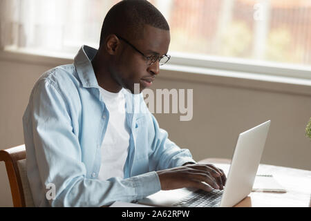 Ernsthafte konzentrierte junge afrikanische amerikanische Mann Remotes Arbeiten mit Computer. Stockfoto