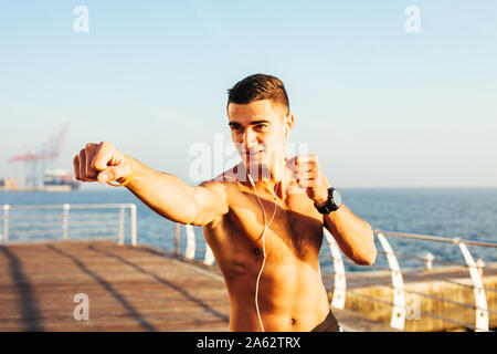 Sportlicher Kerl Boxen auf Schulung durch das Meer Stockfoto