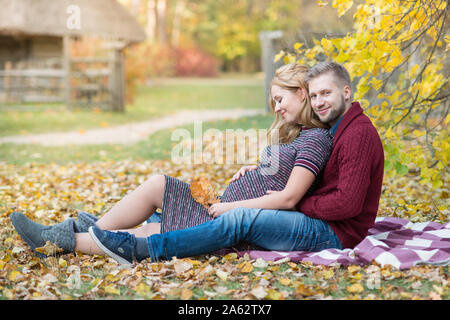 Schöne schwangere Frau mit ihrem Mann zu Fuß im Herbst Park Stockfoto