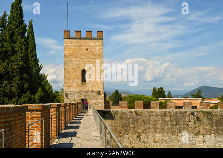 Angesichts der erhöhten Laufsteg auf der Stadtmauer von Pisa mit einem Eckturm und ein Tourist zu Fuß von hinten im Sommer, Toskana, Italien Stockfoto