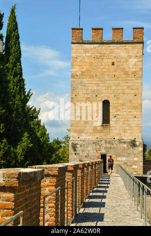 Angesichts der erhöhten Laufsteg auf der Stadtmauer von Pisa mit einem Eckturm und ein Tourist zu Fuß von hinten im Sommer, Toskana, Italien Stockfoto