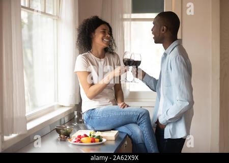 Freudige junge schwarze Frau sitzt auf der Arbeitsplatte, jubeln mit Ehemann. Stockfoto