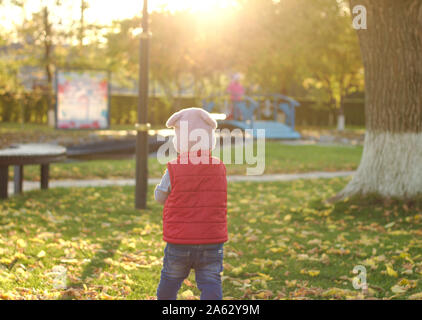 Ein fröhliches Kind streut einen Armful gelbe Laub. Sonnige Sonnenuntergang im Herbst Park im Freien Stockfoto