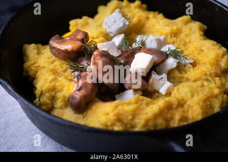 Traditionelle Osteuropäische mais Brei (mamaliga, Polenta, banosh, Balmes) mit Schafskäse, Pilz Soße gekrönt, gebratene Fleischstücke Stockfoto