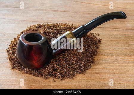 Holz- rauchen Rohr auf einem Haufen Tabak braun Holz- Hintergrund. Rauchen als eine Gewohnheit oder ein Hobby. Rauchen Zubehör. Vorderansicht. Stockfoto