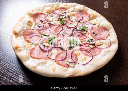 Billige Pizza mit Salami, Zwiebeln und Pilze. Stockfoto